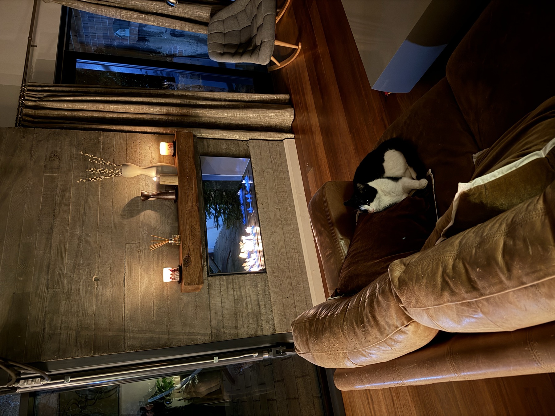 The fireplace at night, candles on the mantel, the tuxedo cat on the sofa
